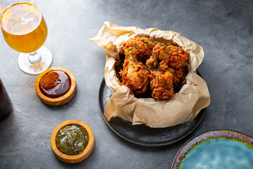 Bowl of deep fried chicken wings with bbq souse and beer on gray table