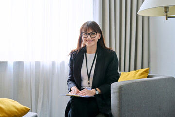 Portrait of middle-aged woman with clipboard sitting in an office chair