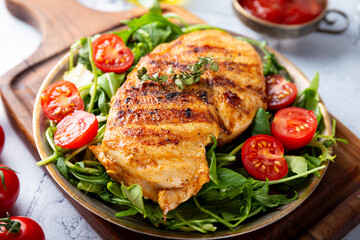 Grilled chicken breast with arugula and tomatoes on a plate