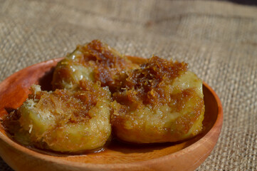 Kue Lupis is a traditional Indonesian sweet sticky cake made from glutinous rice with grated coconut and palm sugar syrup. Selective focus.