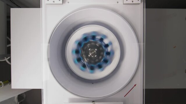 Modern laboratory centrifuge with tubes spins during experiment in researching center. Effective device for materials separation in lab
