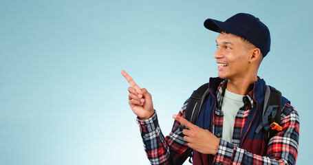 Happy, backpack and man in studio pointing for choice, decision and option on blue background. Travel, tourist mockup and isolated excited person with hand gesture for hiking, adventure and vacation