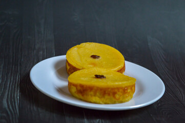 Kue lumpur or Mud cake is a traditional Indonesian cake, made from potatoes, flour, sugar, eggs and coconut milk and then bake with raisins served on white plate. Selected focus.