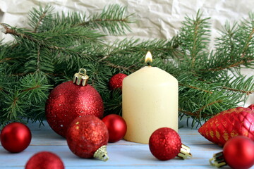 A candle stands on a wooden table with Christmas decoration.