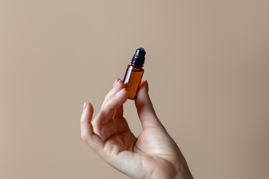 Aroma rollerball with natural aromaoil in woman hand on plain background