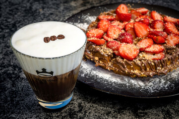 Close-Up of Cappuccino Freddo and Waffle with Strawberry Topping in a Blurred Background.  ideal for coffee shop, dessert, or brunch-themed projects. Selective focus.