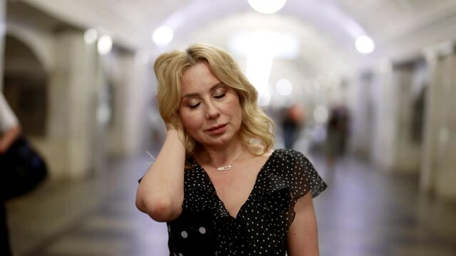 portrait of romantic middle-aged woman in metro, crowds of people walking in blurred background