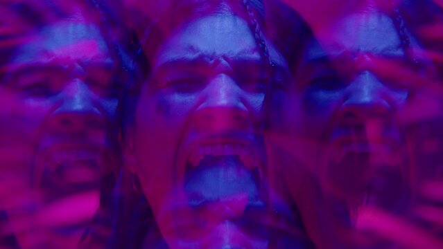 Kaleidoscope effect footage of young frightened woman with leaking mascara emotionally screaming at camera in purple and blue neon illumination