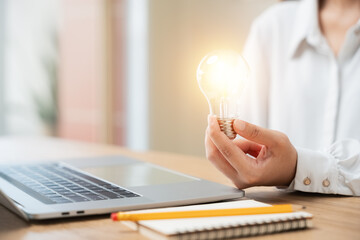 Innovation through ideas and inspiration ideas. businesswoman hand holding light bulb to...