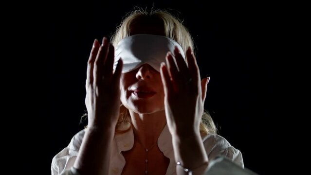 blindfolded woman with sleeping mask on eyes, medium portrait in darkness