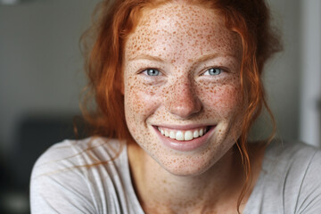 Fototapeta premium The close up face portrait of a young and beautiful woman with red ginger hair and natural freckles showing her smiling while looking at the camera. Generative AI.