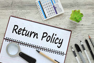 return policy text on the open diary page. near a pen and a plant in a pot