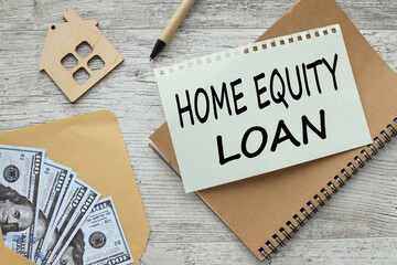 Home Equity Loan money bills in an envelope. figurine of a wooden house. text on a notepad