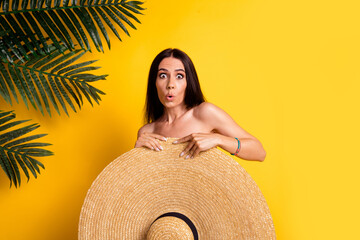 Photo of pretty impressed lady wear bikini hiding behind big sun hat empty space isolated yellow color background