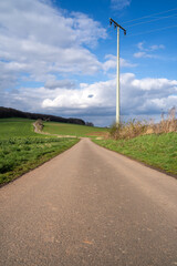 Fototapeta na wymiar Long footpath in the landscape with blue cloudy sky in spring