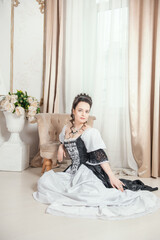 Young beautiful smiling woman in rococo style medieval dress sitting on the floor