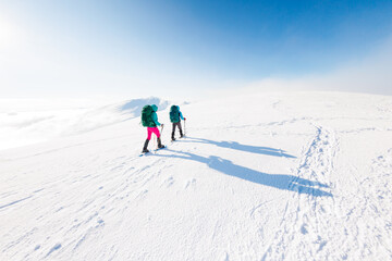 climbers climb the mountain in the snow. Winter mountaineering. two girls in snowshoes walk through the snow. mountaineering equipment. hiking in the mountains in winter.