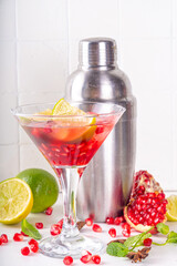 Pomegranate martini cocktail, iced cool boozy drink with fresh pomegranate juice, whiskey and lime slices, white background copy space