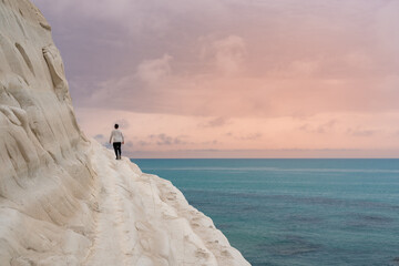 Young man admiring the white limestone cliffs of the Scala dei Turchi, Agrigento, Sicily, Italy, 