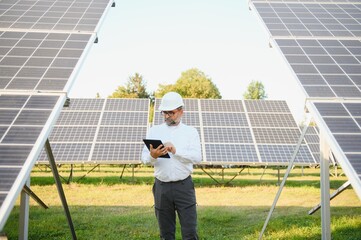 Solar power plant. Man standing near solar panels. Renewable energy