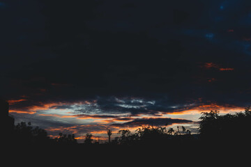 Beautiful sunset sky in dark shades. The sunset breaks through the black clouds.