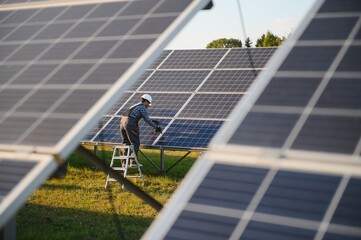 An Indian male worker is working on installing solar panels in a field