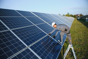 An Indian worker in uniform and with tools works on a solar panel farm