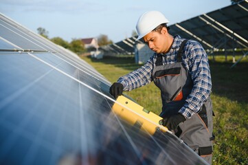 An Indian male worker is working on installing solar panels in a field