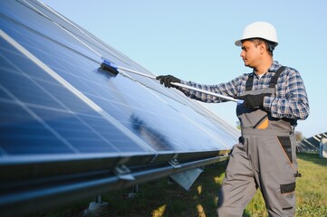 Indian handyman cleaning solar panels form dust and dirt