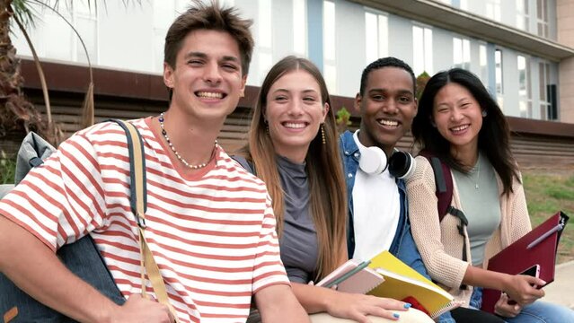 Diverse people smiling sitting outside holding folders. Multicultural group of happy students looking at camera with backpacks and notebooks