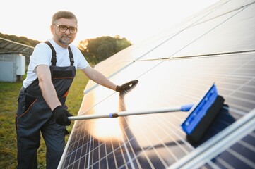 Naklejka premium Worker cleaning solar panels after installation outdoors.