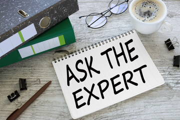 ASK THE EXPERTS a cup of coffee. glasses. two office folder gray notepad. text on the page