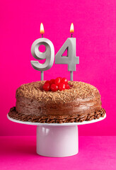 Number 94 candle - Chocolate cake on pink background