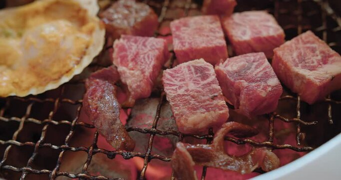 Close up grilling roasting fresh juicy meat beef slices on charcoal grill, Japanese style yakiniku grill in restaurant