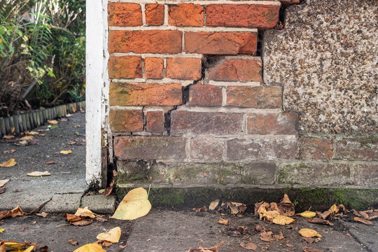 Cracked brick wall in need of repair on boundary of residential premises.