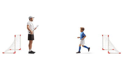 Boy training football with a coach on mini goals