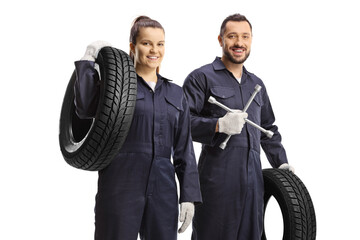Male and female car mechanic workers holding lug wrench tool and a car tire