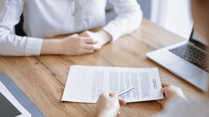 Businesswoman lawyer pointing into contract special points admitting something for colleague or client at the wooden desk in office. Business people teamwork and partnership, meeting concept