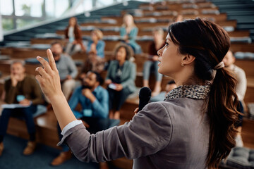 Businesswoman speaking to group of entrepreneurs during an education event at convention center.