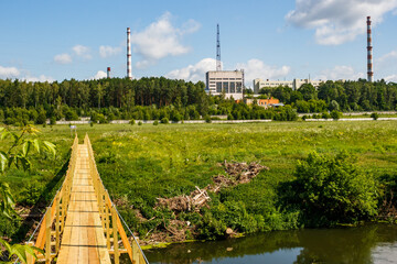 View from the side of a wooden bridge to an industrial area with tall pipes