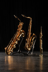 Three golden saxophones on stands on the concert stage. Shallow depth of field.