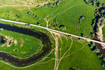 Aerial photo of land with trajectories of country roads and river bends among a green landscape
