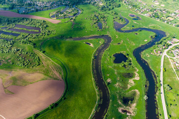 Landscape from the air, an elongated and winding river bed among green fields. Old lake Ogublyanka,...