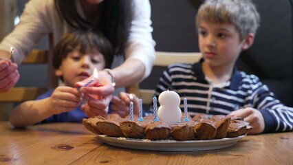 Birthday scene celebration, children lighting candles during 8 year old boy celebration. two...