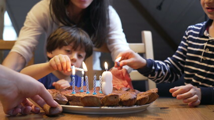 Birthday scene celebration, children lighting candles during 8 year old boy celebration. two brothers in front of cake - obrazy, fototapety, plakaty
