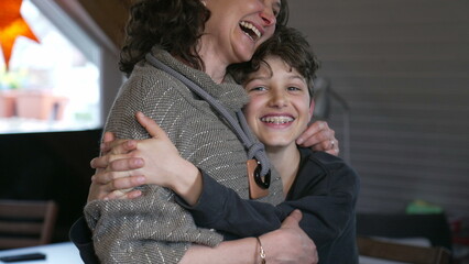 Candid mother and pre-teen boy laughing together. Authentic moment of family lifestyle joy with...