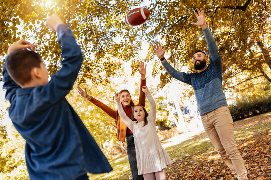 Family playing american football in park. Family and kids, nature concept.