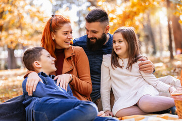 Parents tickle their children. Sunny autumn day in the colorful park