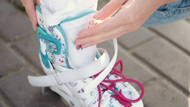 Mon helping her daughter in the park rollerblading enjoying there time together helping her daughter put on the safety on her hands