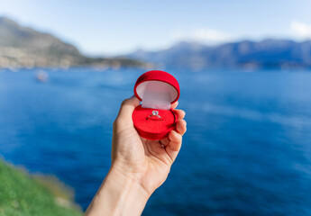 Engagement ring in a red velvet box for a marriage proposal while traveling around Europe and the world - in Italy on Lake Como